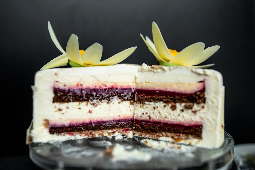Berry fruit confit layers cut cleanly inside a vanilla mousse entremet
